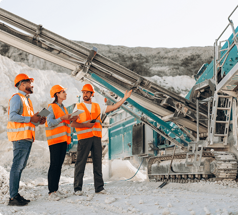 Construction workers inspecting heavy machinery at site.