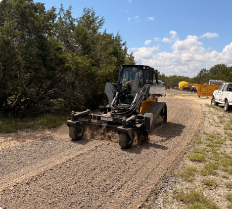 Loader facing camera grooming a gravel road