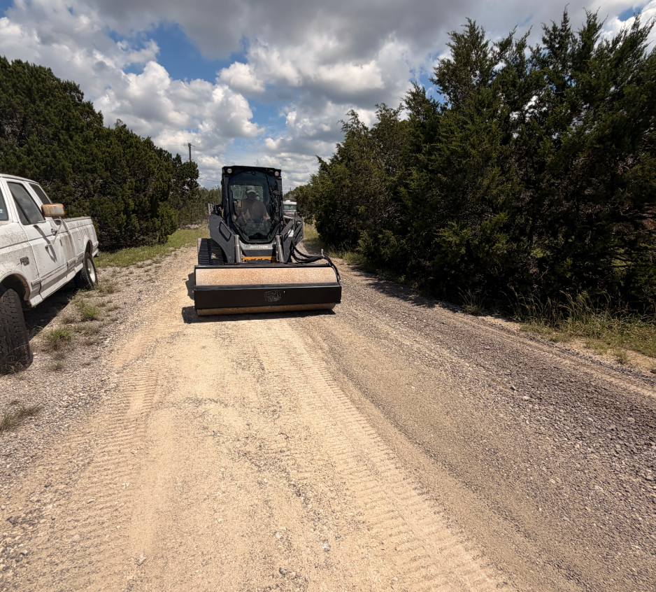 Small broom attachment smoothing rural gravel road