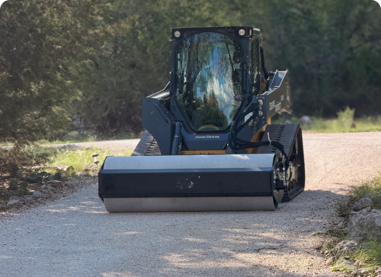 Compact track loader rolling gravel driveway