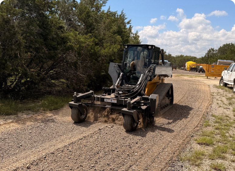 Tracked machine grading gravel driveway