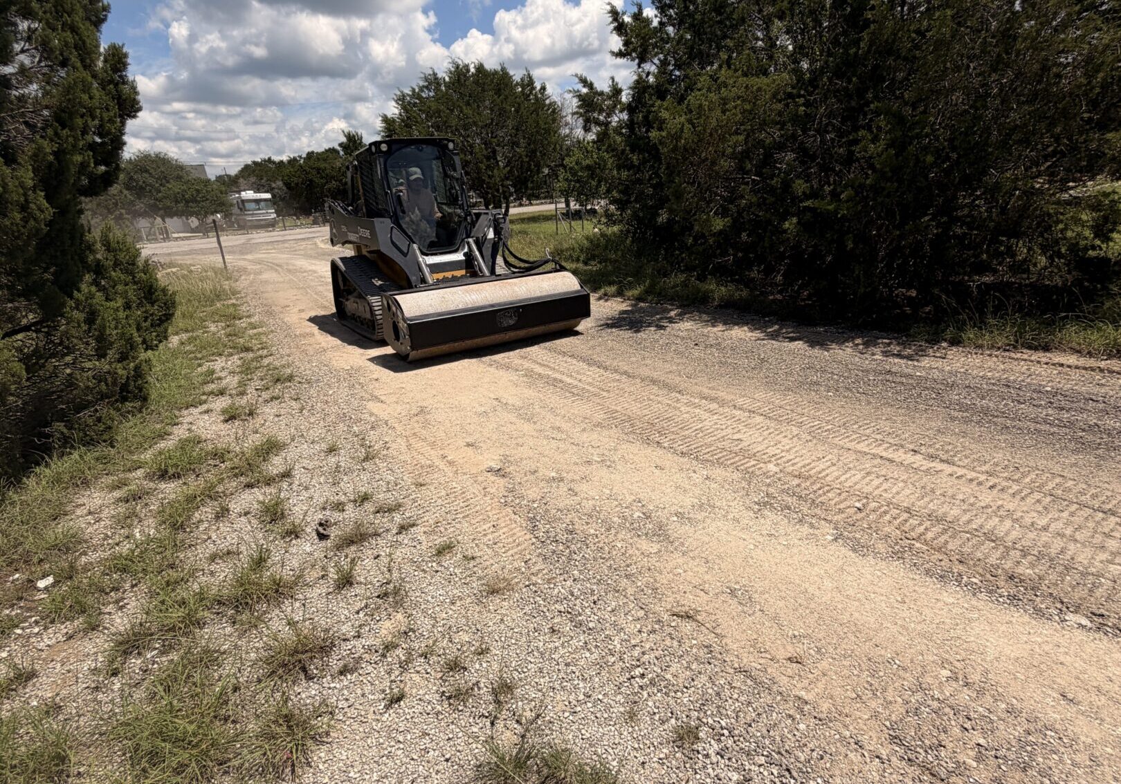 Compact loader smoothing a rural gravel road