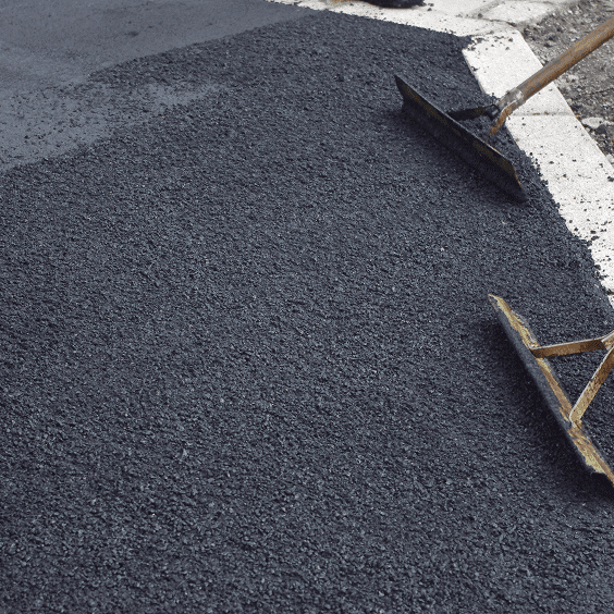 Rakes spreading asphalt on a road surface.